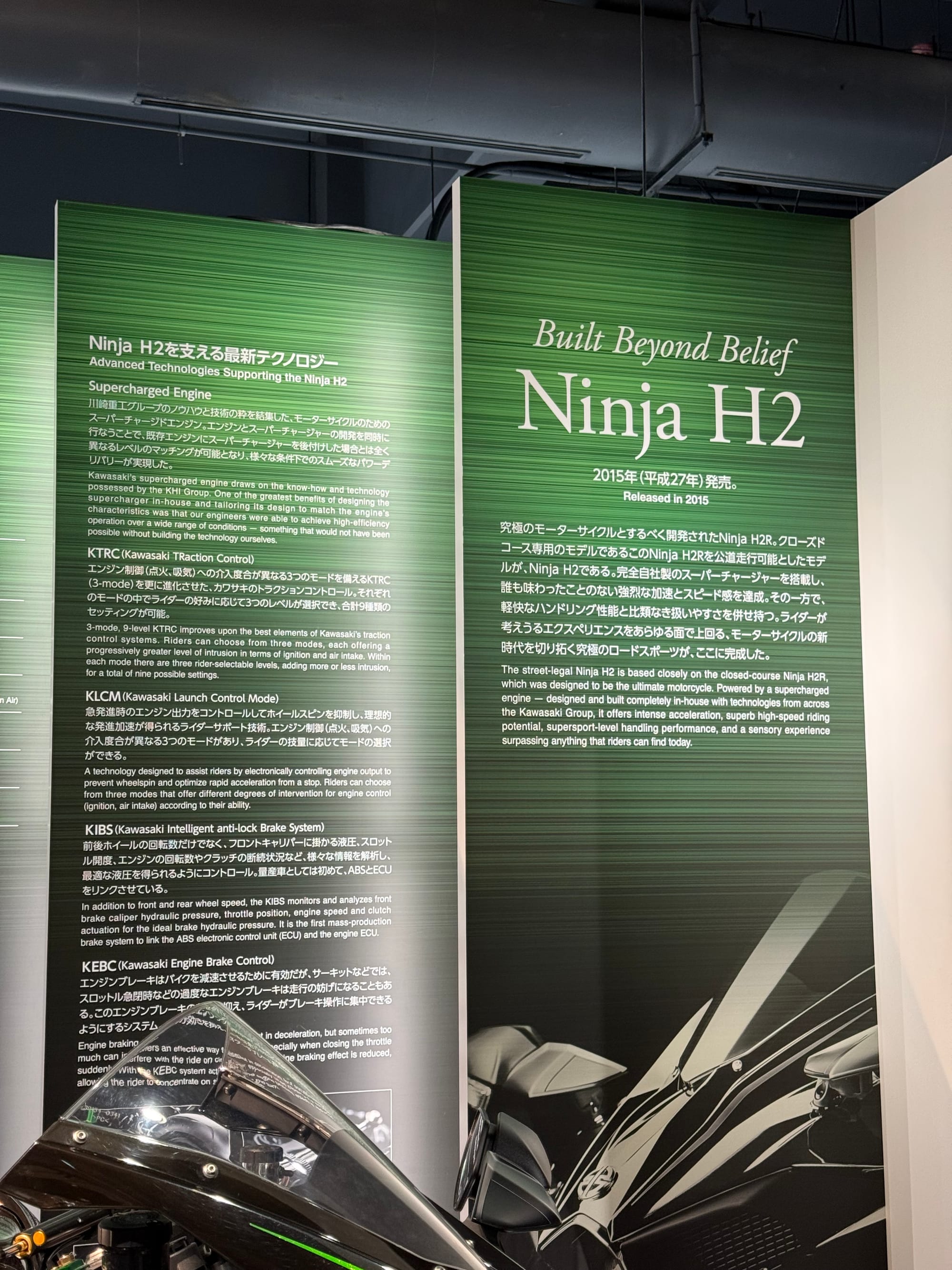 Ninja H2 exhibit panel at Kawasaki Good Times World, outlining the motorcycle's supercharged engine and advanced technologies, including traction control and launch control.