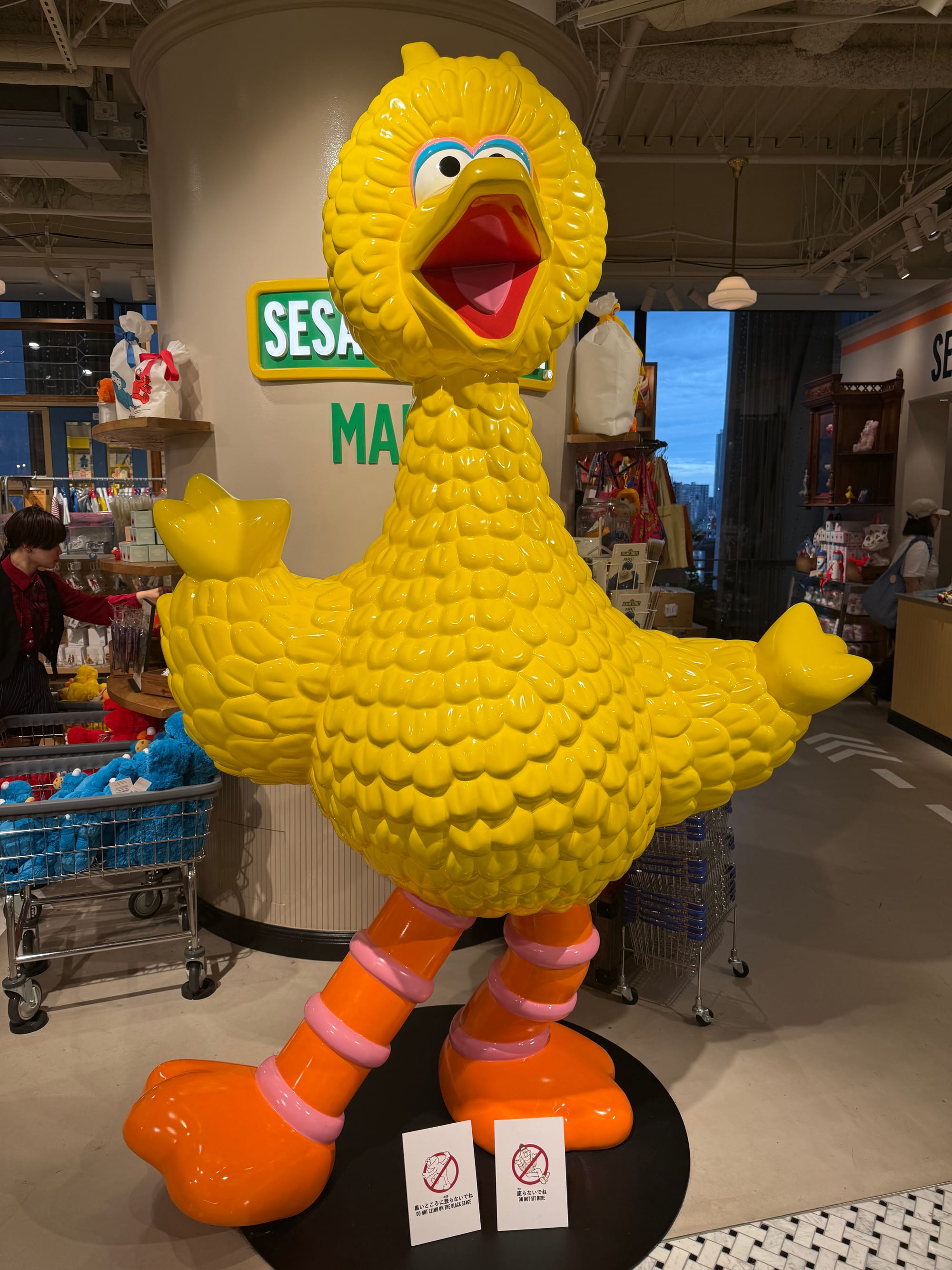 Large Big Bird statue inside a Sesame Street store in Osaka, featuring the bright yellow character standing with outstretched wings among merchandise and colourful displays.