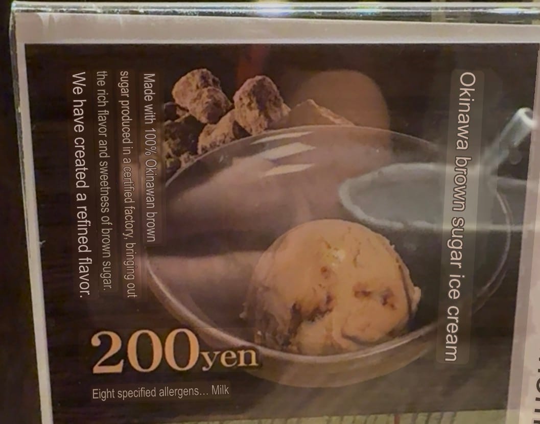 Menu card advertising Okinawa brown sugar ice cream, featuring a scoop of ice cream in a glass bowl, brown sugar pieces and a description of the Okinawan ingredient.