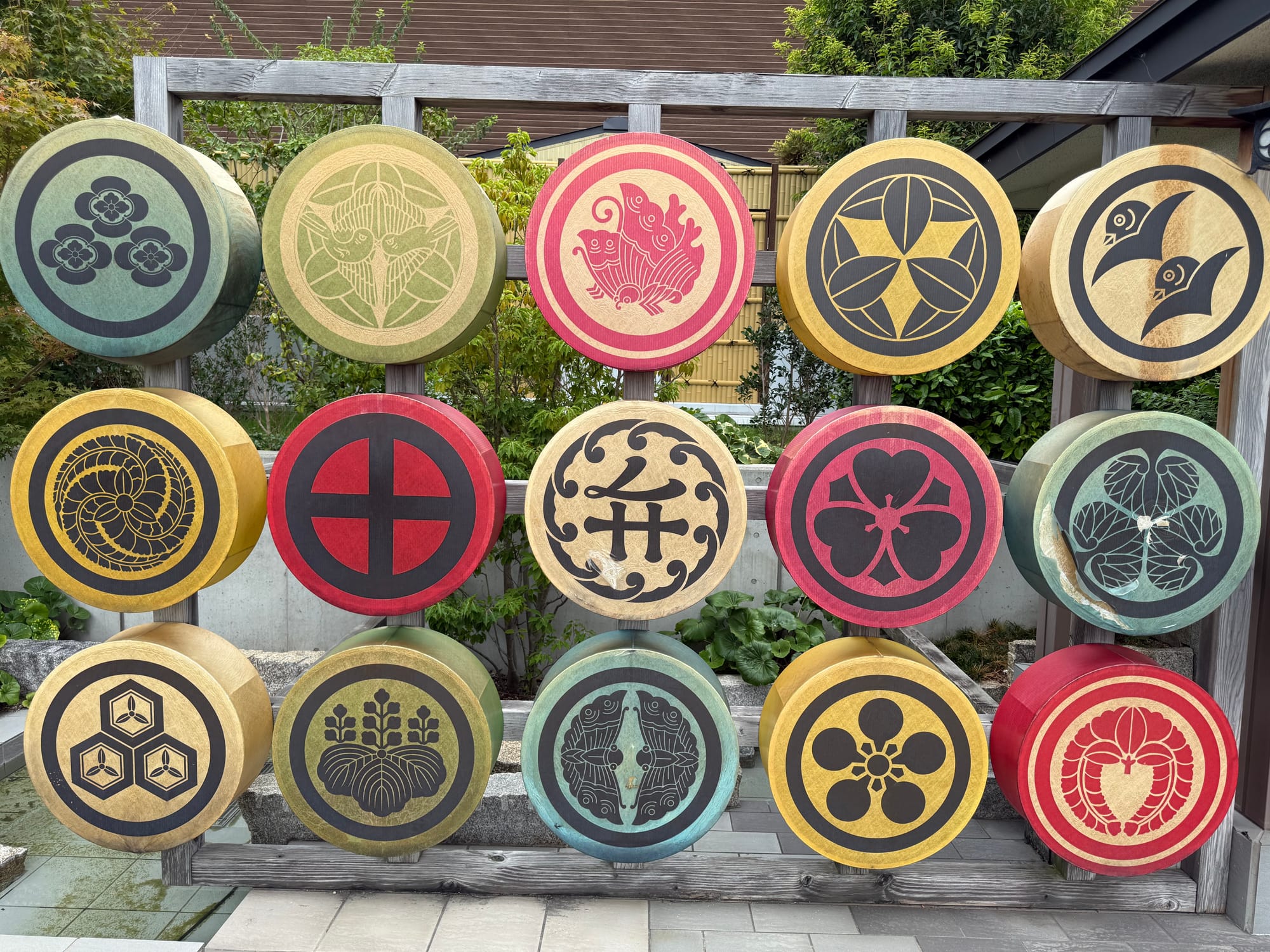 Display of circular Japanese family crest designs (kamon) in the rooftop garden at Solaniwa Onsen Osaka Bay Tower, featuring colourful emblems mounted on a wooden frame.