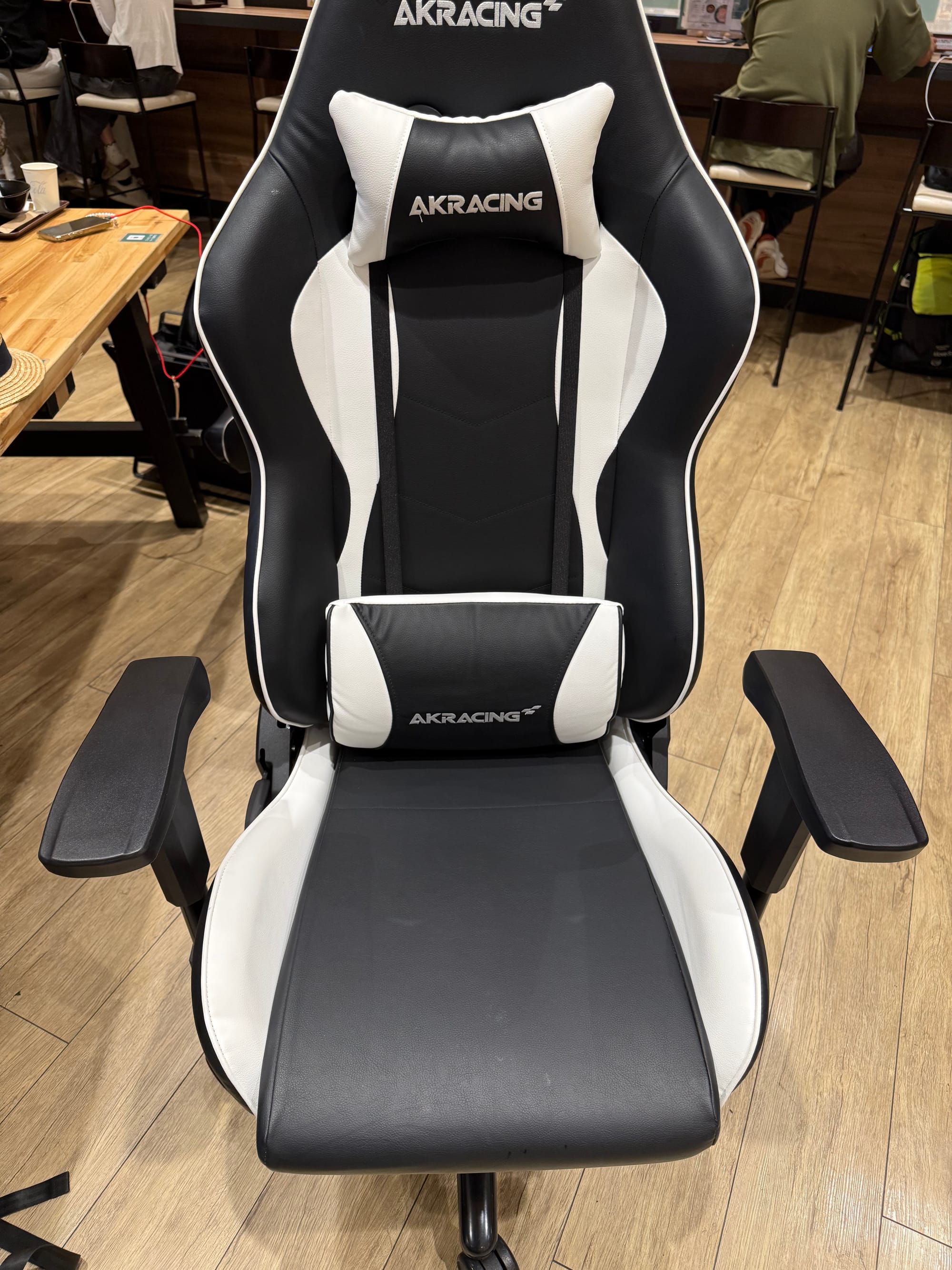 AKRacing gaming chair in the Nodoka airport lounge at Kansai International Airport, featuring adjustable armrests, lumbar and neck cushions, and a black-and-white design.
