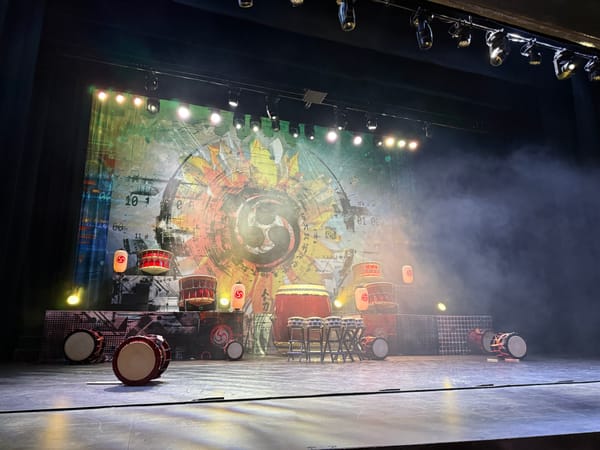 Stage set with Japanese taiko drums, lanterns, dramatic lighting, and light fog before a performance.
